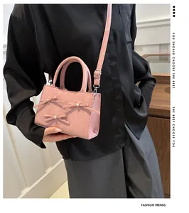 Close-up of pink crossbody bag featuring decorative bows and white pearl accents