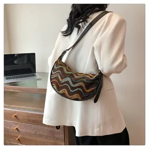 Detail of hobo shoulder bag with colorful wave embroidery and leather strap on model