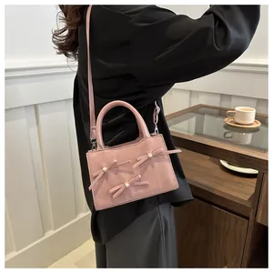 Pink lady's crossbody bag featuring decorative bows and white pearls detail