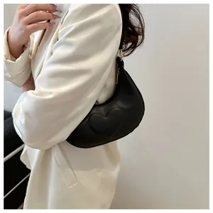 Detail der schwarzen Hobo-Tasche mit Herzprägung und goldenem Ring am Schulterriemen
