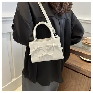 Detail of white pearl bow bag featuring litchi texture leather and elegant metal strap