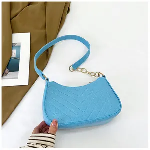 Detail of blue quilted felt crescent bag with gold chain and leather shoulder strap
