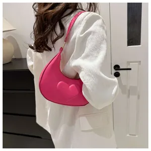 Detail der pinken Halbmond-Tasche mit geprägtem 3D-Herz und goldener Metallschnalle