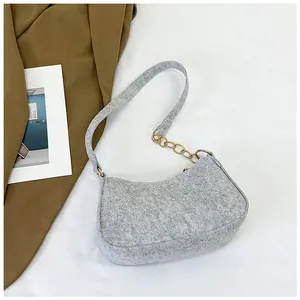 Close-up of a light gray felt shoulder bag with a stylish gold metal chain strap detail
