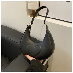 Details der matt-schwarzen Halbmandtasche mit Herzrelief und goldenen Metall-Elementen