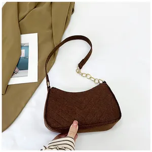 Close-up of dark brown felt hobo bag with V-shaped quilting and gold chain link detail