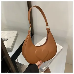 Nahaufnahme braune Halbmond-Tasche mit 3D-Herzdetail und goldener Hardware