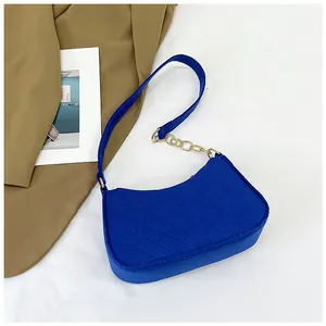Detail of royal blue felt shoulder bag with V-shaped quilting and gold metal chain