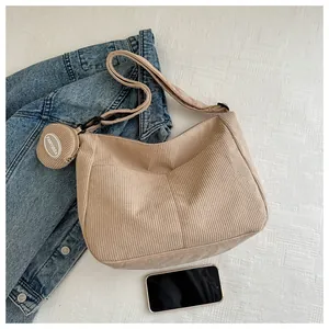 Detail of khaki corduroy hobo bag with adjustable strap and small round coin purse charm