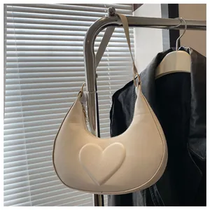 Detail der cremeweißen Halbmond-Tasche mit 3D-Herzprägung und mattem Leder-Finish