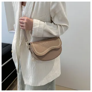 Primer plano de bolso montura caqui con costuras acolchadas y detalles de cadena oro