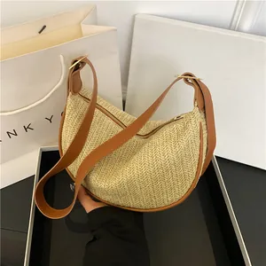 Minimalist beige woven half-moon handbag with brown leather trim and golden zipper