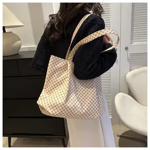 Vue détaillée du sac cabas beige avec motifs géométriques marron porté à l'épaule