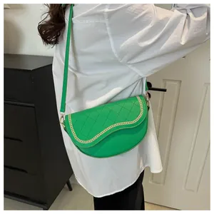 Detalle de bolso silla verde vibrante con acolchado de rombos y adorno de cadena dorada