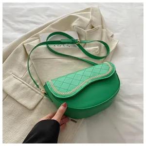 Detalle del bolso silla acolchado verde con cadena dorada y correa de hombro ajustable