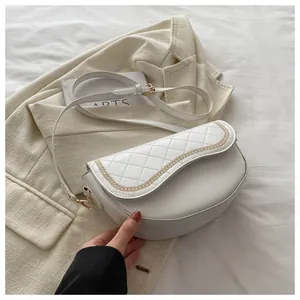 Detalle del bordado acolchado y la cadena dorada en este bolso de hombro blanco tipo silla