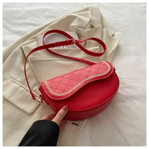 Detalle del bolso de montura rojo acolchado con borde de cadena dorada y asa ajustable