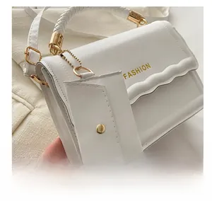 Détail du sac à main blanc avec poignée tressée et petit charm en forme d'enveloppe