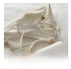 Détail du sac blanc avec poignée tressée et fermeture dorée sur le rabat