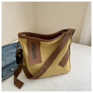 Dettaglio della borsa tote in tela giallo senape con toppa in pelle e tracolla regolabile