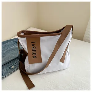 Dettaglio della borsa tote in tela bianca con finiture marroni e logo FASHION