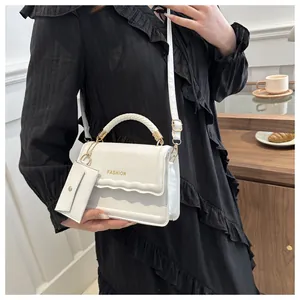 Vue détaillée du sac à main tissé blanc avec lettrage doré et mini pochette amovible