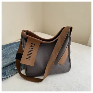 Dettaglio della borsa tote in tela con etichetta fashion e tracolla in tessuto marrone