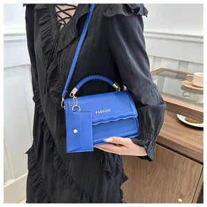 Détail du sac à main bleu avec poignée tressée, lettrage et mini porte-monnaie assorti