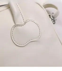 Close-up of cherry blossom stitch detail on cream white minimalist faux leather handbag
