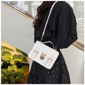 Detailed side view of white leather messenger bag with gold hardware worn by a model