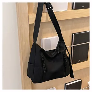 Détail du sac bandoulière en nylon noir avec deux poches zippées et bandoulière réglable
