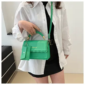 Vue détaillée du sac à main vert vif tissé avec rabat ondulé, chaîne dorée et pochette