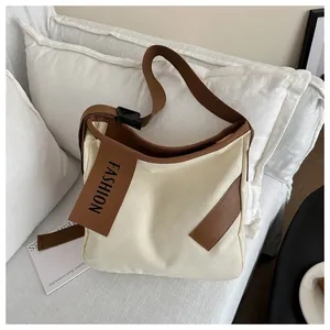 Dettaglio della borsa tote in tela crema con finiture in pelle marrone e tag FASHION
