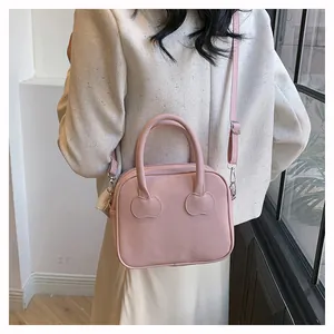 Close-up of pink leather handbag with cherry stitch detail and adjustable shoulder strap