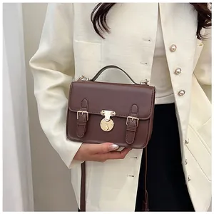 Detail of a dark brown retro messenger bag with golden metal buckles and handle