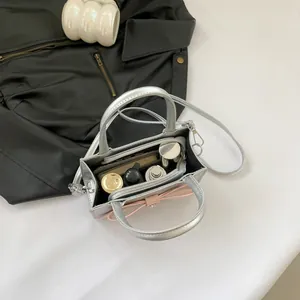 Silver patent leather handbag with pink bow showing spacious interior and items