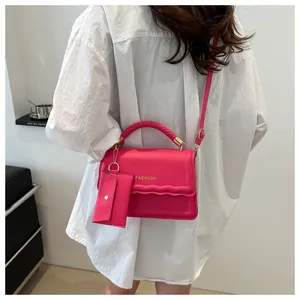 Détail du sac rose avec poignée tressée, rabat festonné et inscription fashion dorée