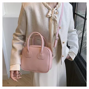 Detailed close-up of pink crossbody bag with heart-shaped handle patches and smooth finish