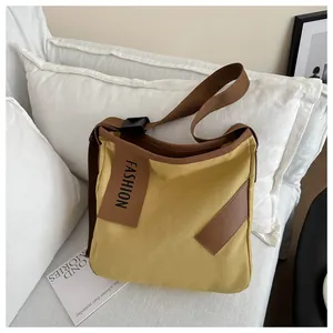 Dettaglio borsa tote in tela con tracolla regolabile e toppa in pelle in giallo zenzero