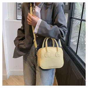 Detail of light yellow mini handbag showing heart-shaped stitching and adjustable strap