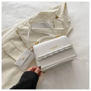 Détail du sac blanc à poignée tressée avec rabat ondulé et mini porte-monnaie