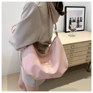 Détail du sac cabas plissé rose avec étiquette dorée et fine bandoulière élégante