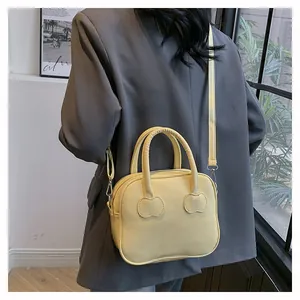 Minimalist light yellow crossbody bag with decorative panels shown on a female model