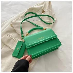 Détail du sac à bandoulière vert avec poignée tissée et accents métalliques dorés
