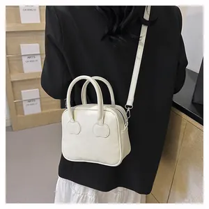 Close-up of cream square handbag with cherry leather patches and detachable strap