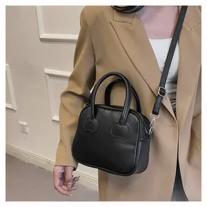 Detail view of black PU leather handbag featuring unique heart-shaped handle stitching and strap