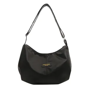 Grand sac cabas hobo noir avec étiquette mode et bandoulière réglable au style minimaliste