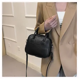 Detail of black matte leather handbag with heart-shaped accents and detachable strap
