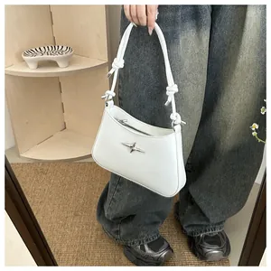 Detail of white leather crescent bag with silver star decor and knotted strap details