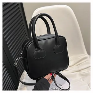 Detail of black PU leather bag with cloud-shaped handle attachments and zip closure